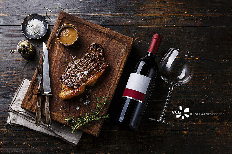 烤牛排，胡椒酱和一瓶红酒，木质背景图片素材