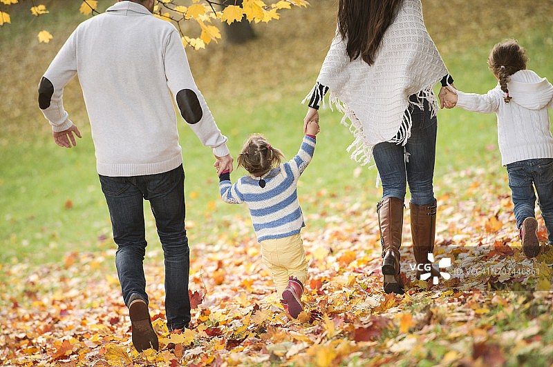 幸福的家庭和两个女孩在秋叶中散步图片素材