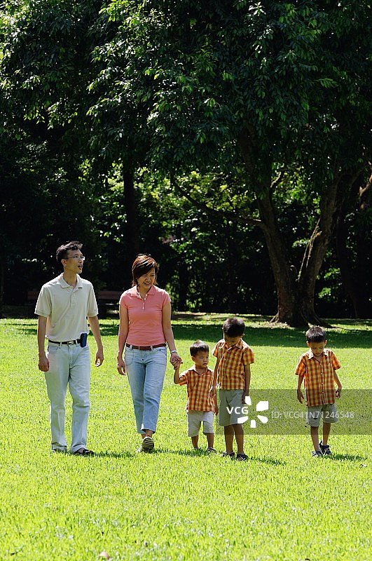 一家人带着三个男孩在公园散步图片素材