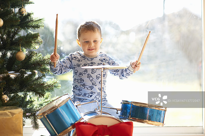 男孩在圣诞节玩玩具架子鼓图片素材