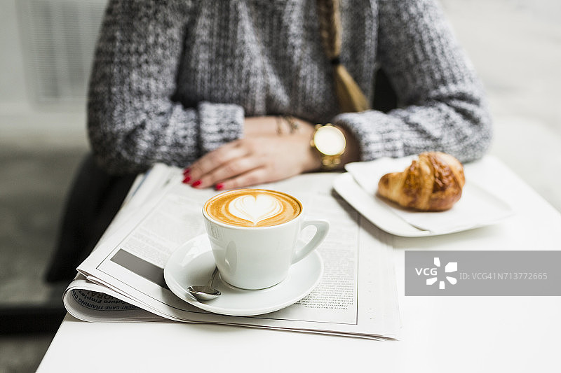 女人坐在商店里，端着咖啡和报纸图片素材