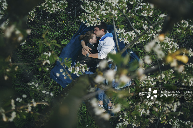 一对白种人夫妇躺在花树下的草地上图片素材