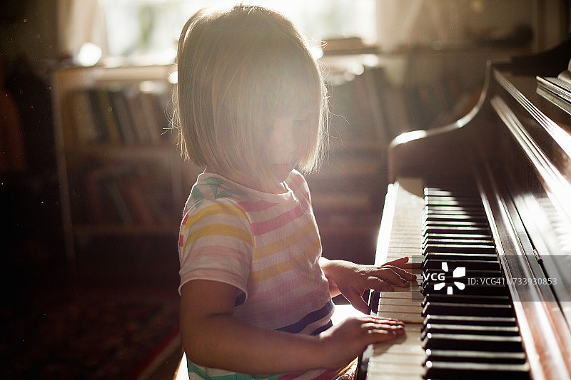 女孩在家里弹旧钢琴图片素材