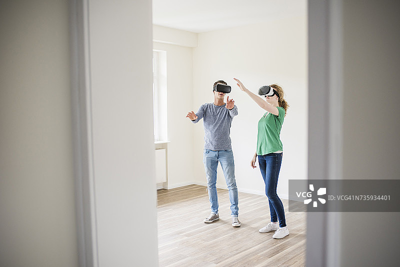 一对年轻夫妇戴着虚拟现实眼镜在空荡荡的公寓里讨论图片素材
