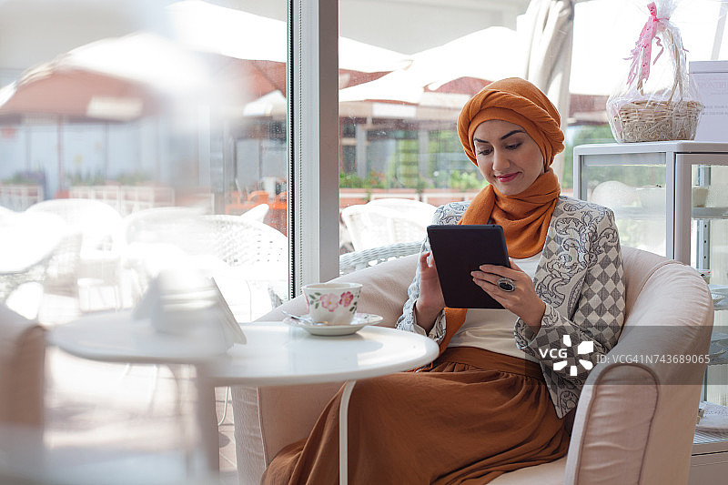 阿拉伯妇女在café上使用Ipad。图片素材