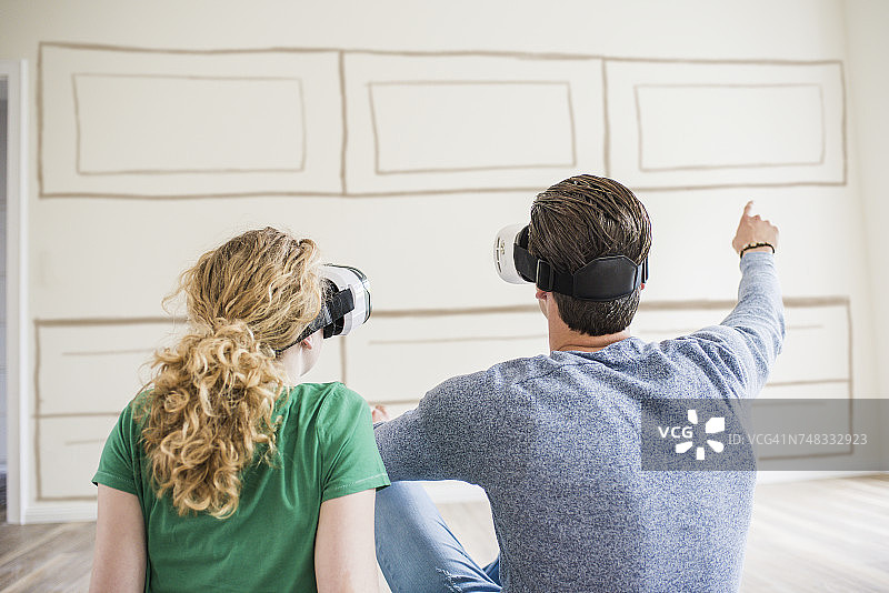 一对年轻夫妇在新家戴着VR眼镜思考室内设计图片素材