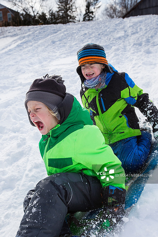 男孩们骑着雪橇，在雪地上滑行图片素材