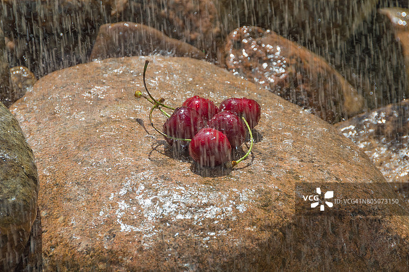 近距离看，雨中的樱桃躺在岩石上图片素材