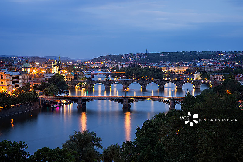 捷克共和国布拉格伏尔塔瓦河上灯火通明的建筑物和桥梁，在黄昏时从高处俯瞰。图片素材