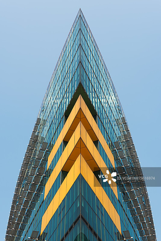 现代的玻璃建筑，三个黄色的人字形映衬着蓝色的天空图片素材