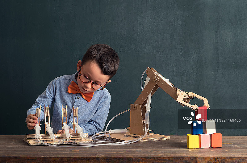 可爱的孩子发明了带有纸板的机器人手臂。图片素材