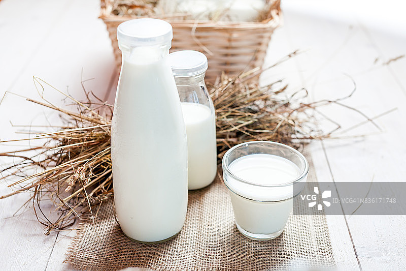 牛奶和几杯牛奶放在一张质朴的木头桌子上。图片素材