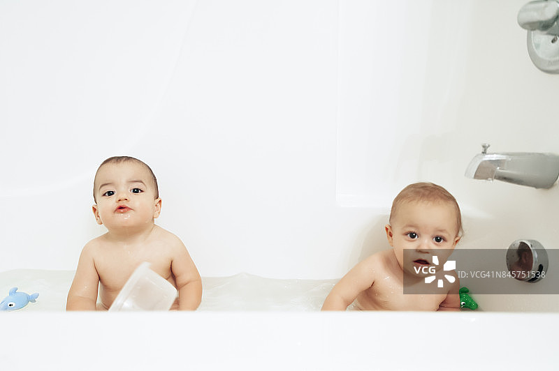 一对一岁的双胞胎男孩一起在浴缸里玩图片素材