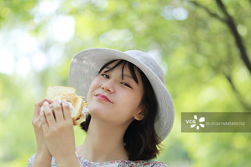 一个一边吃面包一边看镜头的女人的面部表情图片素材