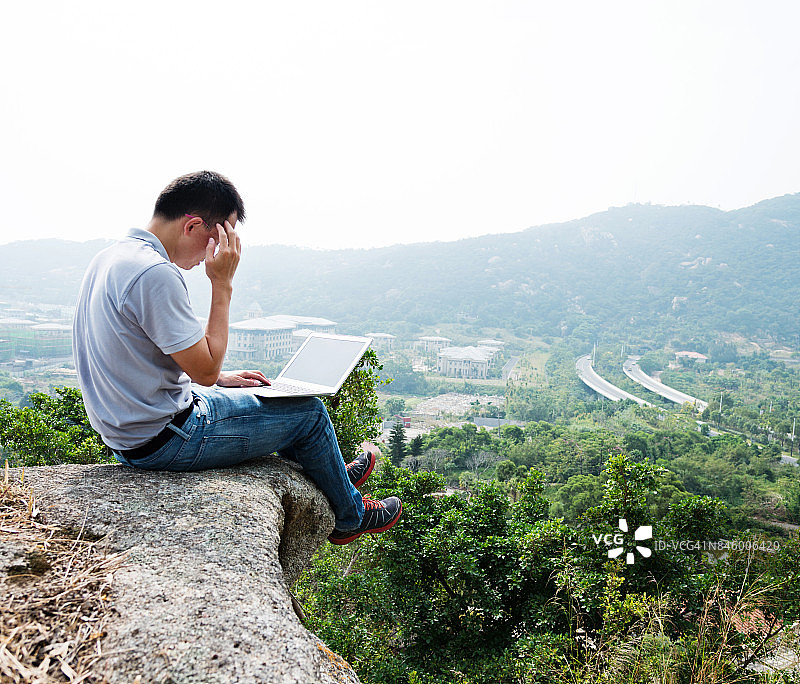一个人站在悬崖边用笔记本电脑图片素材