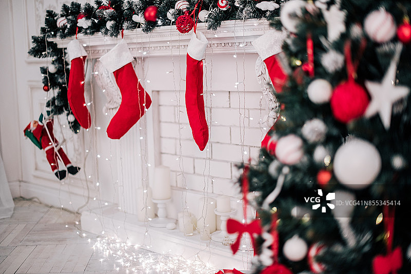 一个漂亮的装饰明亮的红色圣诞袜挂在壁炉等待礼物的特写。图片素材
