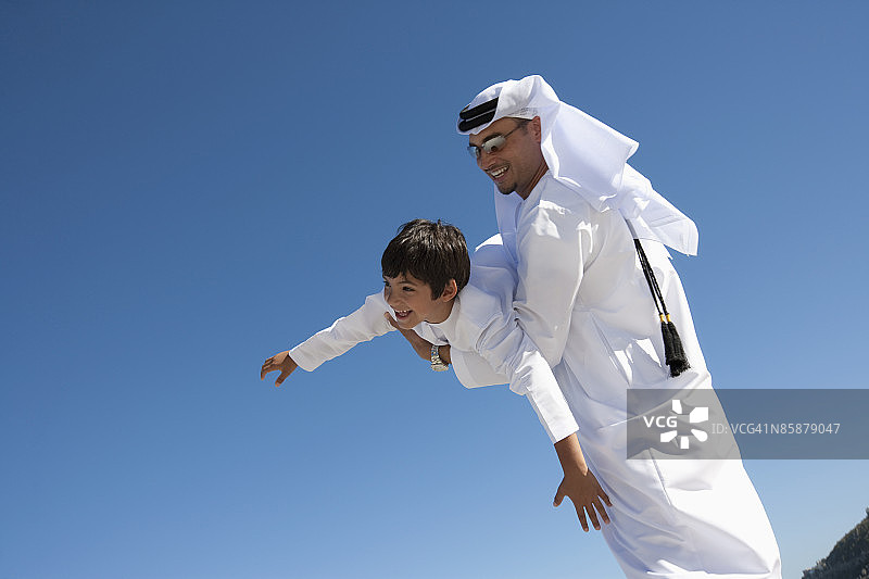 阿拉伯男子将男孩举向天空。图片素材
