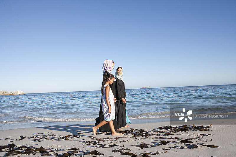 两个阿拉伯女人和一个女孩在海滩上。图片素材