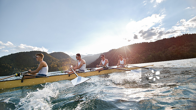 下午晚些时候，四名男运动员划船横渡湖泊图片素材