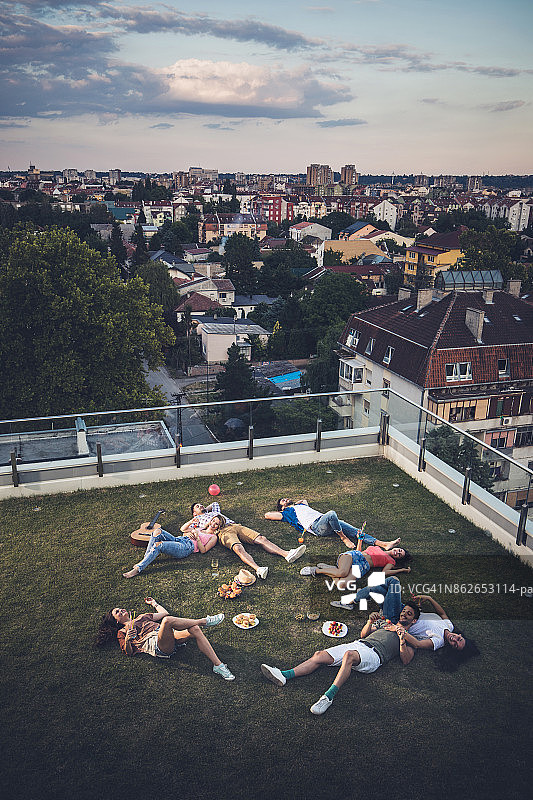 上面的观点，快乐的朋友放松在草地上的顶层露台。图片素材