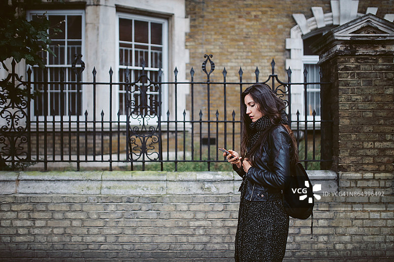 一名年轻女子在伦敦街头边走边发短信图片素材