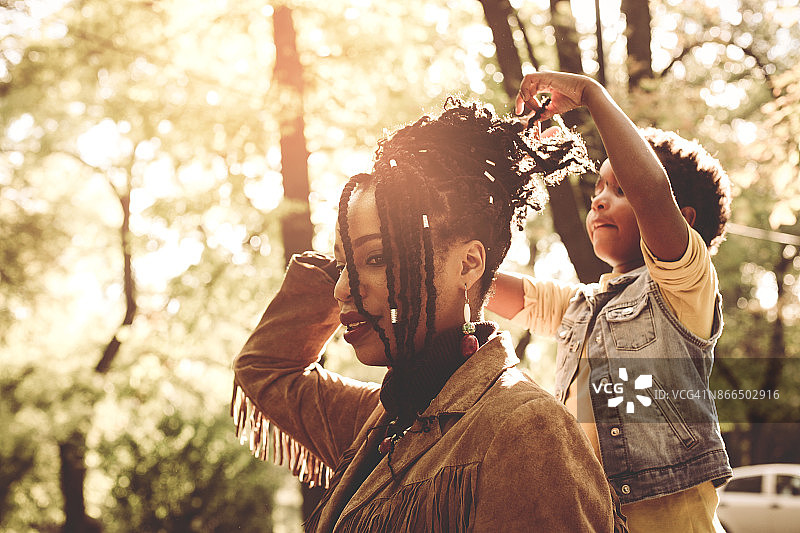 非裔美国小女孩在公园里给妈妈做发型。图片素材