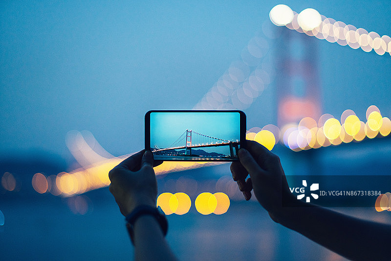 黄昏时分，一名女子用智能手机拍下了青马桥的照片图片素材