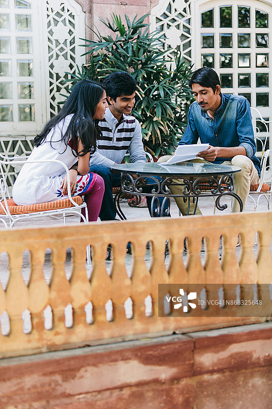 一群印度千禧一代围坐在露台上看文件。图片素材