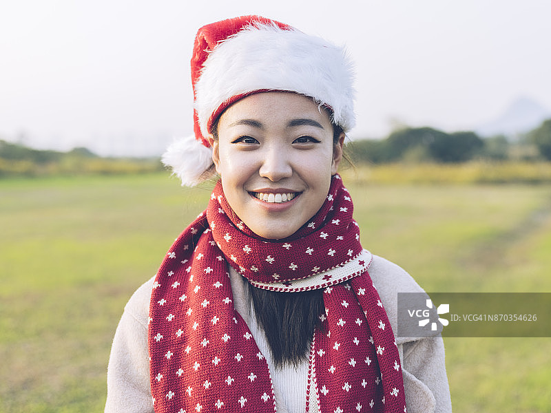 亚洲妇女的肖像与圣诞老人帽子微笑的相机图片素材