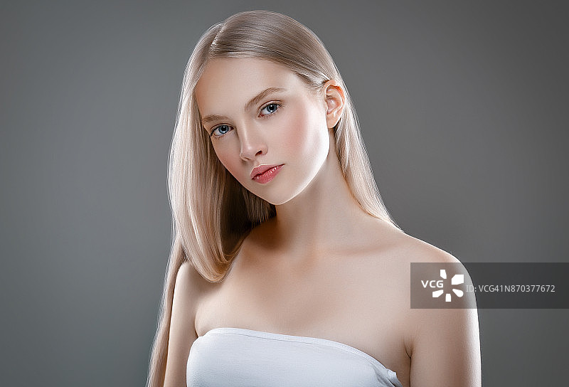 美丽的女人面部肖像美丽的皮肤护理概念与长金发。灰色背景下美丽发型的模特图片素材
