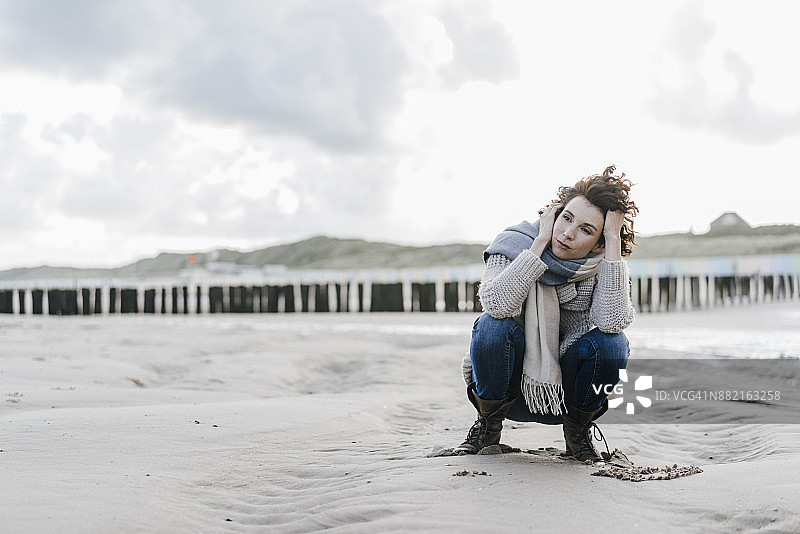 一个女人蹲在沙滩上图片素材