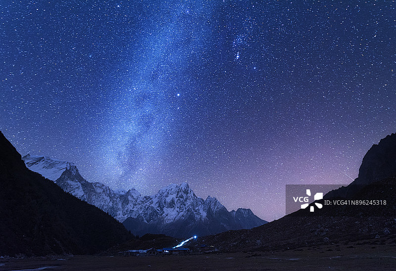 银河和山脉。美丽的喜马拉雅山脉和尼泊尔夜晚的星空。白雪皑皑的岩石和满天繁星。美丽的喜马拉雅山脉。夜景与明亮的银河图片素材