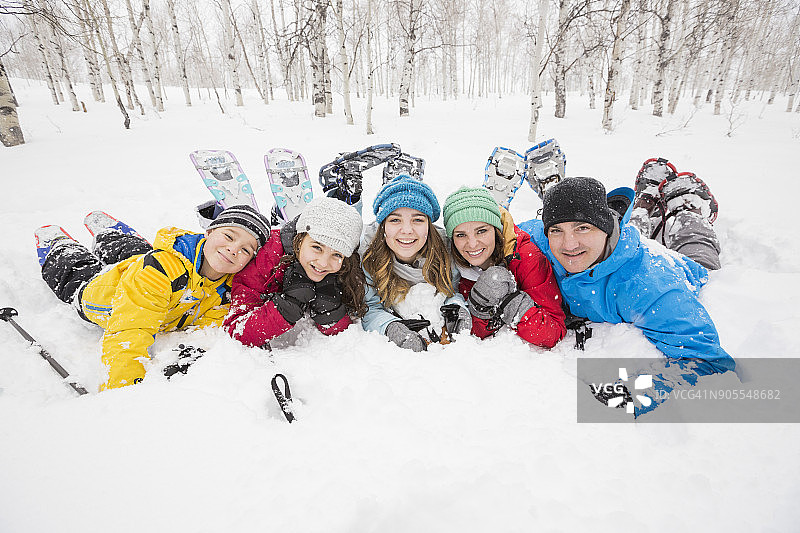 微笑的白人家庭躺在雪地里的肖像图片素材