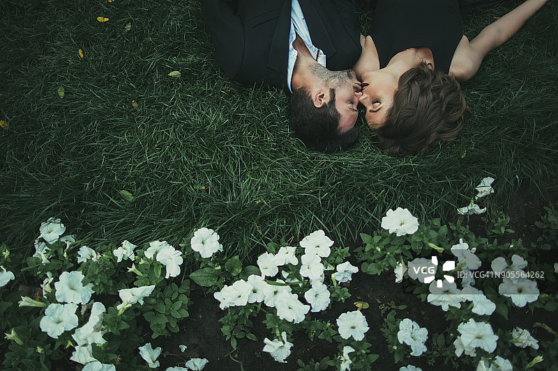 一对白种夫妇躺在草地上接吻图片素材