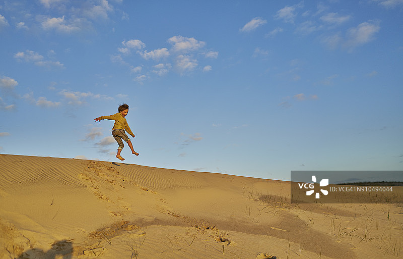 男孩在半空中跳下沙丘，波洛尼奥，罗查，乌拉圭，南美图片素材