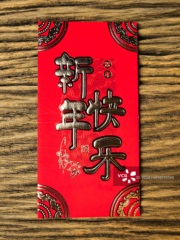 木制背景的红色信封，以二月作为春节礼物。信封上的中文文字寓意春节快乐图片素材