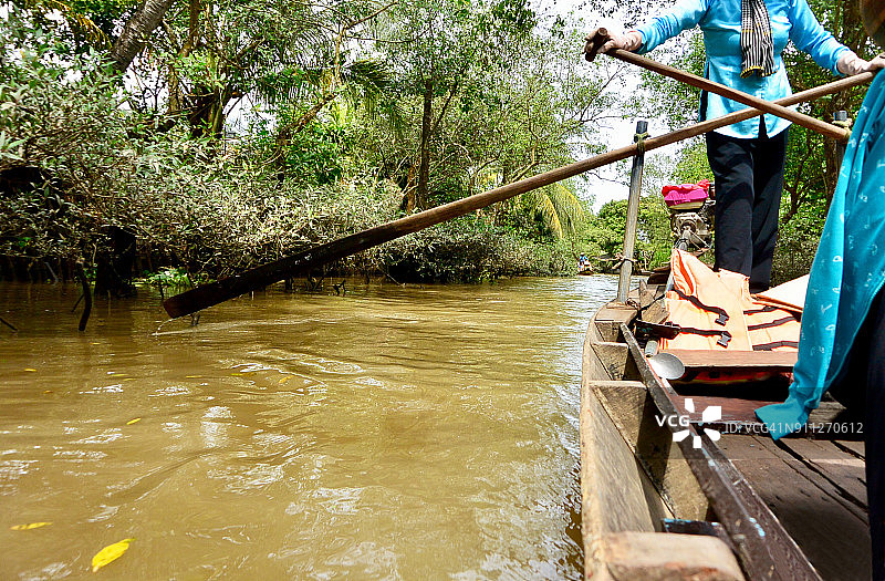 越南湄公河三角洲运河上的女子划着长桨图片素材