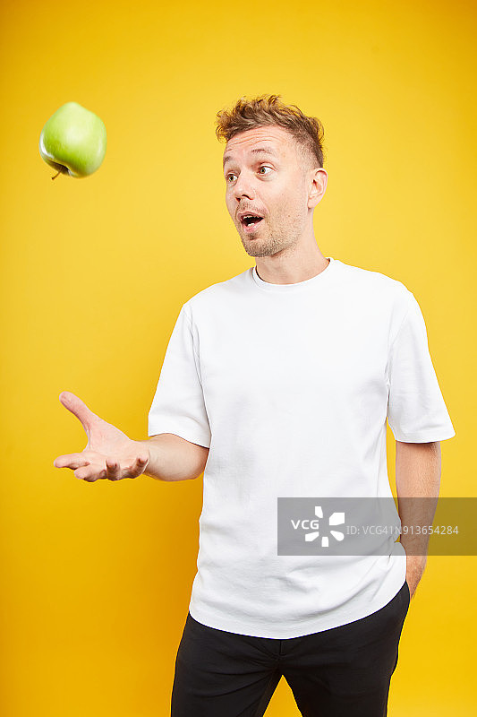 一个男人在彩色背景上拿着一个苹果图片素材
