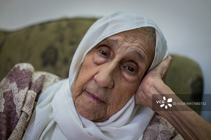 非常老的穆斯林妇女坐在家里的沙发上思考图片素材