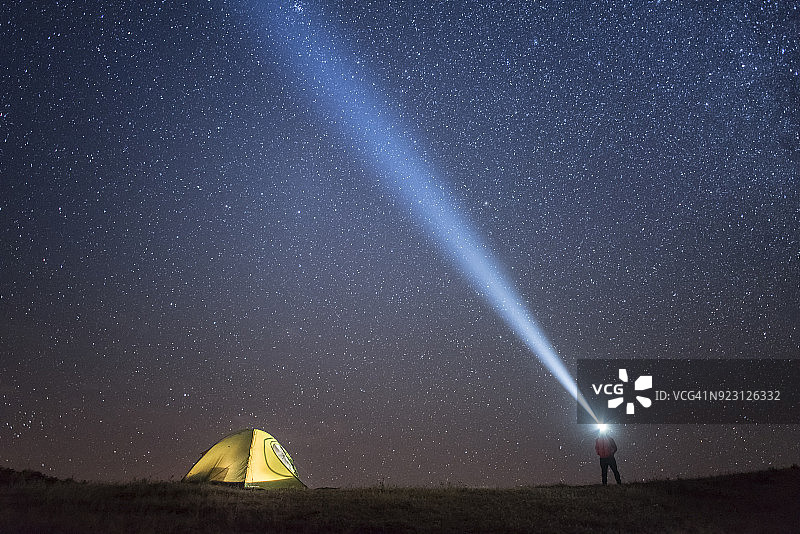 银河系和星空上的银河带着露营帐篷和人们带着手电筒图片素材