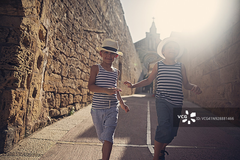 快乐的游客们在地中海街道上奔跑。图片素材