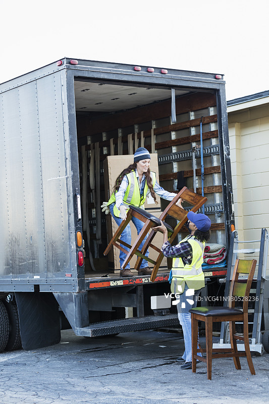 两个女工开着卡车，搬运家具图片素材