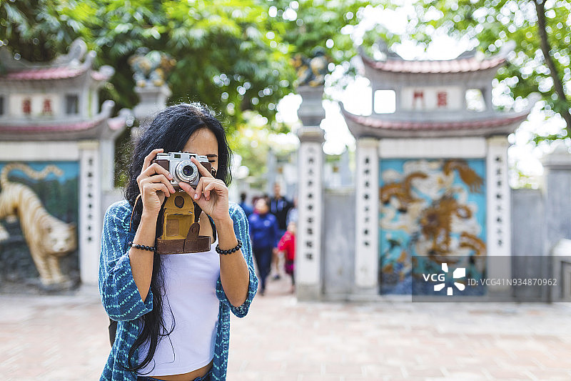 越南，河内，一名年轻女子正在用老式相机拍照图片素材