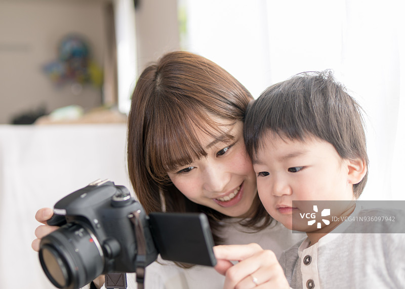 年轻的母亲和儿子在查看相机上的照片图片素材