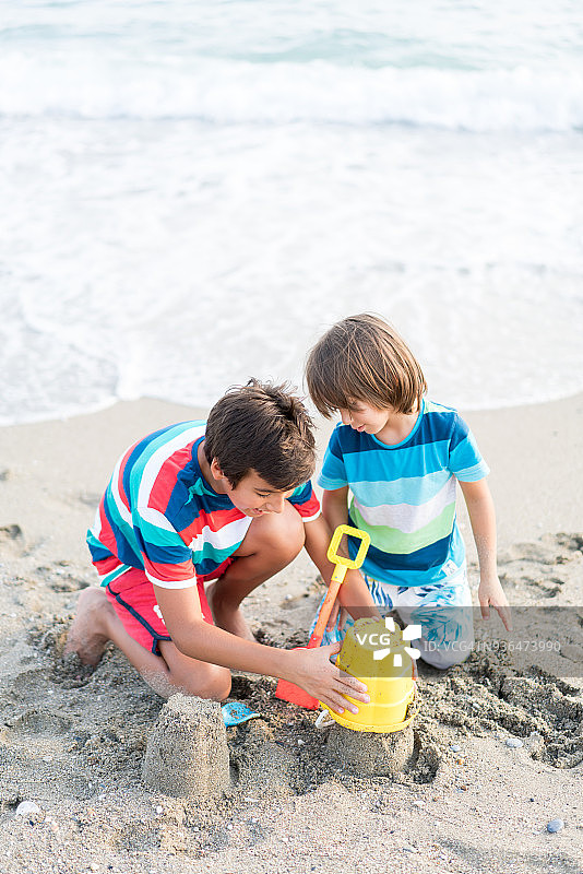 沙滩上的两个男孩在建造沙堡图片素材