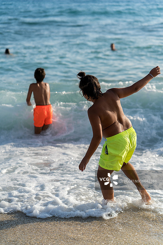 两个十几岁的男孩在海滩上的水里跑步图片素材