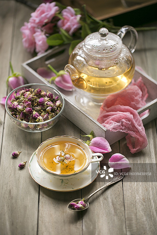 装饰杯中的玫瑰茶在木制桌面上。图片素材
