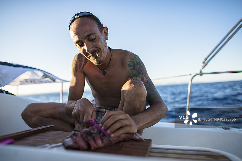 西班牙马略卡岛，一名男子在帆船上切金枪鱼片图片素材