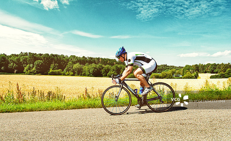 夏日里，一名男子在乡间小路上骑自行车图片素材