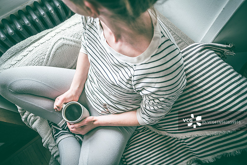 年轻女子一边喝着咖啡，一边在沙发上休息图片素材